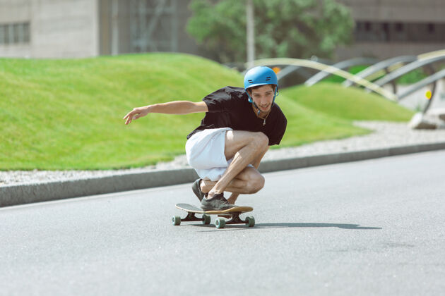 极限在阳光明媚的日子里 在城市街道上玩滑板的人穿着装备的年轻人在沥青路面上骑行和玩长板休闲活动 运动 极限 爱好和运动的概念年轻运动空气
