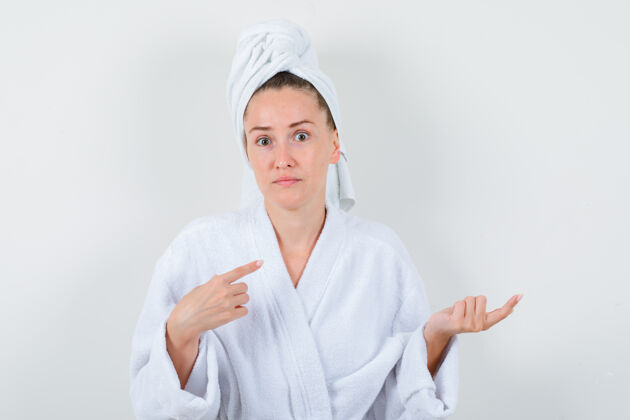 健康穿着白色浴袍的年轻女士 毛巾指着一边 显得优柔寡断 前视图人头发魅力