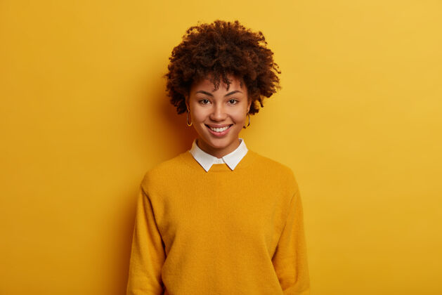非洲裔美女肖像有着欢快的笑容 穿着白领休闲套头衫 站在鲜艳的黄色空间 直视镜头高兴过度运动女性