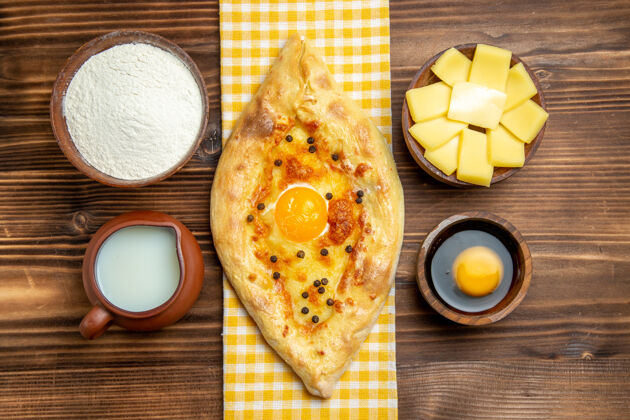 顶部顶视图美味的鸡蛋面包 刚从烤箱里拿出来 在木制桌上放牛奶和奶酪 面包 鸡蛋面包奶酪新鲜午餐