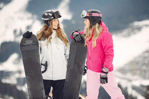 运动装穿着滑雪板套装的女人在山上的运动员手拿滑雪板在地平线上关于运动的概念护目镜板冷