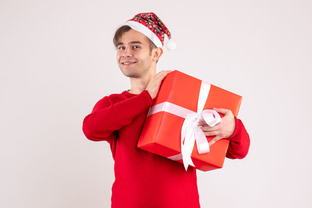 微笑正面图：戴着圣诞帽的年轻人站在白色背景上礼物圣诞节庆祝