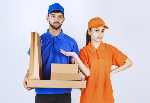 男性穿着蓝黄制服的男女快递员手里拿着纸板外卖盒和购物包效果安全服务
