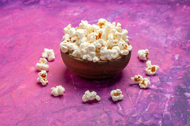 小吃正面看新鲜爆米花在粉红色的桌上玉米电影电影院爆米花食品新鲜爆米花