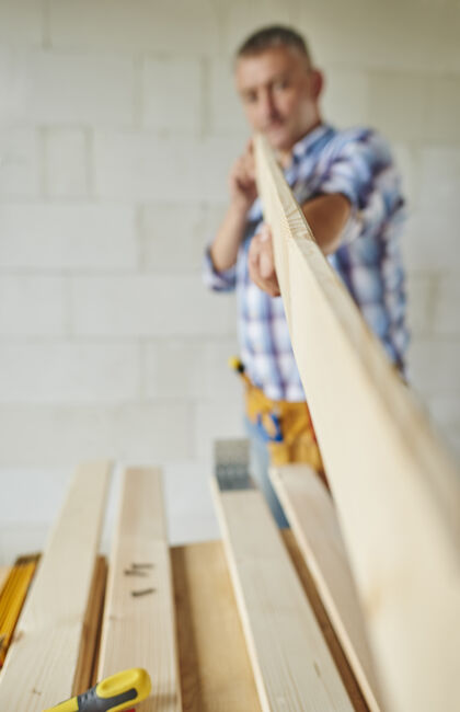 触摸拿木板的高级木匠测量设计离焦