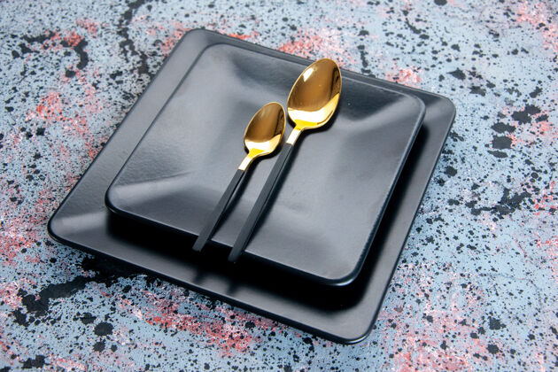 斑点前视图深色盘子和金色勺子在浅色背景上勺子深色盘子晚餐