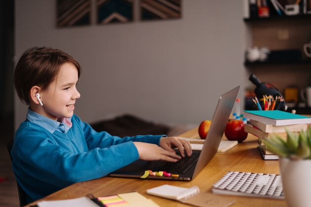 男孩一个未成年男孩用笔记本电脑在线上课耳机技术做笔记