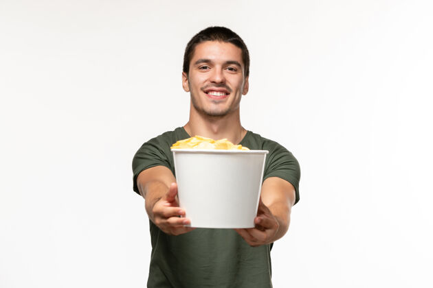 电影正面图身穿绿色t恤的年轻男性手持土豆cips站在白色墙上孤独的电影人视图杯子电影
