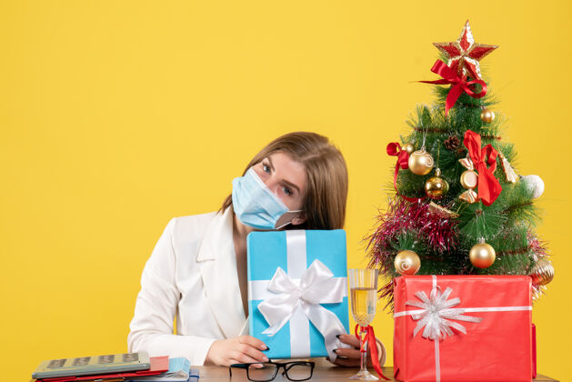 面具正面图：戴着无菌口罩的女医生带着礼物消毒年份圣诞节