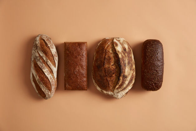 早餐主食和健康营养的概念四种面包隔离在棕色背景上小麦 黑麦 富含维生素和矿物质 有机面粉制成的拼写面包 对健康有好处酸面团平衡新鲜