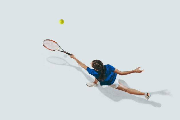活动穿蓝衬衫打网球的年轻女子她用球拍击球游戏健身球