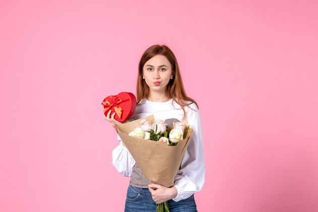 花正面图：带鲜花的年轻女性 在粉色背景上作为妇女节礼物赠送玫瑰横三月女性约会女性爱情平等礼物玫瑰礼物