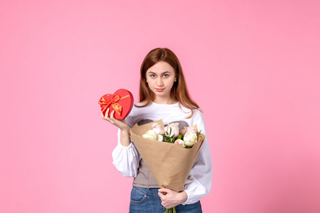 礼物正面图：带花的年轻女性 在粉色背景上作为妇女节礼物赠送玫瑰横三月女性约会爱情感官平等礼物玫瑰年轻女性
