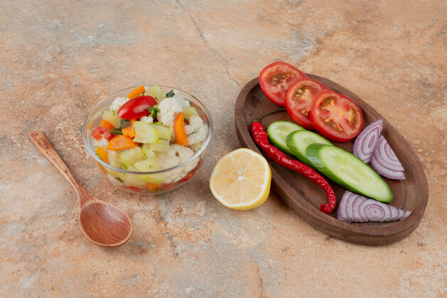 胡萝卜美味的蔬菜放在玻璃盘上 番茄 黄瓜和洋葱的木板放在大理石上盘子美味玻璃杯