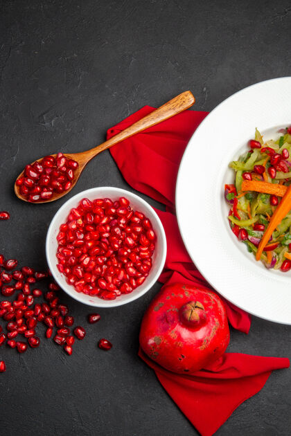 胡椒俯瞰石榴瓜子碗石榴蔬菜色拉红桌布健康浆果盘子