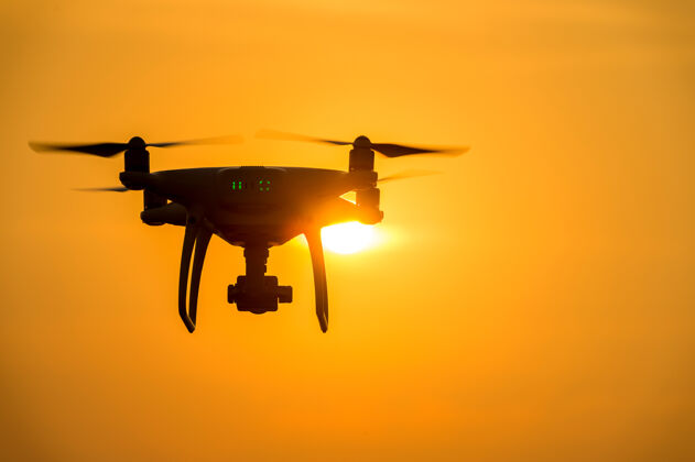 直升机无人机的轮廓与相机在日落时飞行高现代机器人