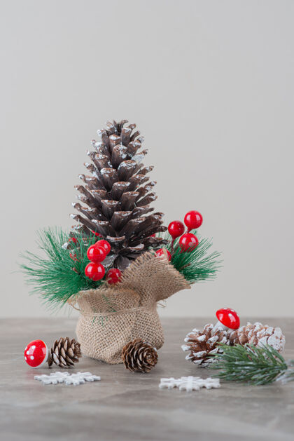 圣诞节用冬青浆果和树枝装饰的松果放在大理石桌上圆锥体松树冬天