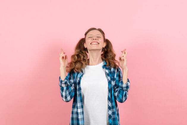 人正面图：穿着格子衬衫的年轻女性在粉色背景上摆姿势 手指交叉 女性青春色彩 儿童模特年轻格子微笑
