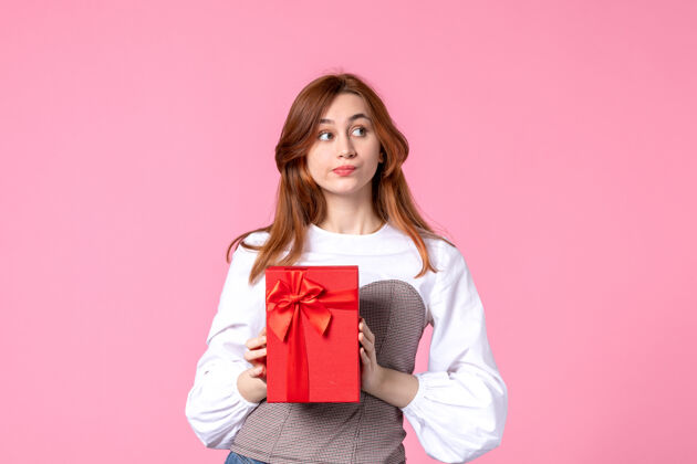礼品前视年轻女性以粉色背景上的红色包装呈现恋爱日期三月横向性感香水女性照片金钱平等礼品年轻女性香水