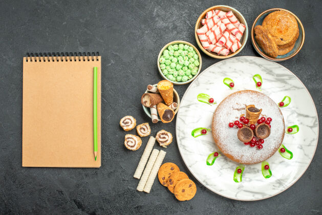 笔记本顶部特写镜头糖果一个蛋糕与红醋栗彩色糖果华夫饼笔记本铅笔早餐葡萄干美食