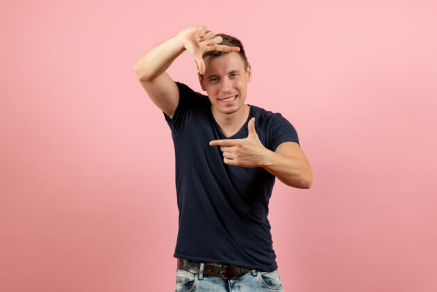 人正面图身着蓝色t恤的年轻男性在粉色背景上展示图片标志男性情感色彩模特人类年轻男性情感成人