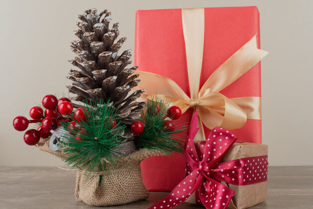 盒子松果装饰冬青浆果和礼品袋在大理石桌上圆锥体冬天礼物