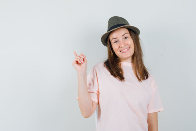 女性戴着粉色t恤帽子的年轻女士指着头 看上去很高兴连衣裙人性化优雅