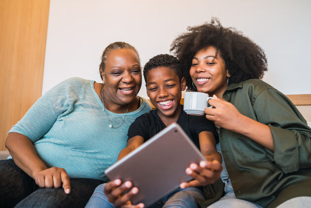 家庭非裔美国人祖母 母亲和儿子在家里用数字平板电脑自拍的画像儿子室内快乐