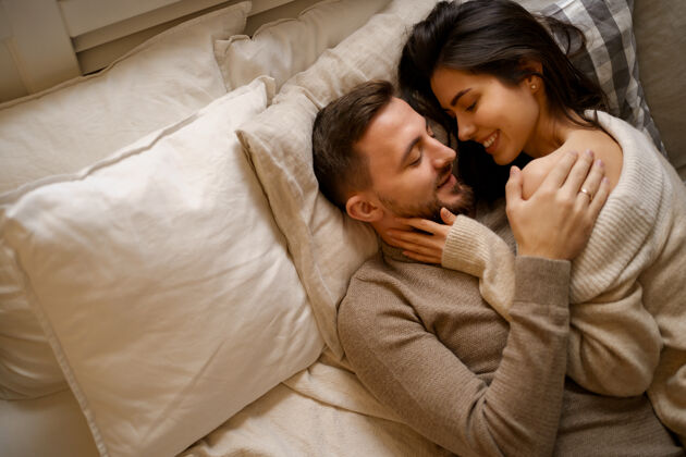 枕头美丽的年轻幸福的夫妇在床上放松 微笑 拥抱卧室舒适室内