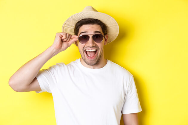 夏天旅游和度假的概念戴着夏日帽子和太阳镜的快乐男人站在黄色背景上享受假期的特写镜头男人男人男人