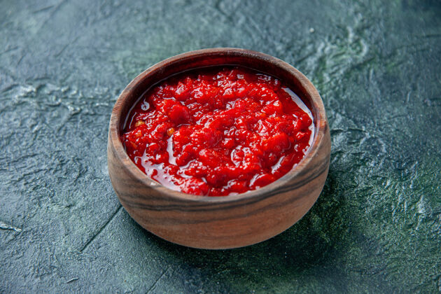 盐正面图番茄酱在深蓝色的表面上棕色的盘子里番茄红色的调味料胡椒盐可食用水果胡椒农产品