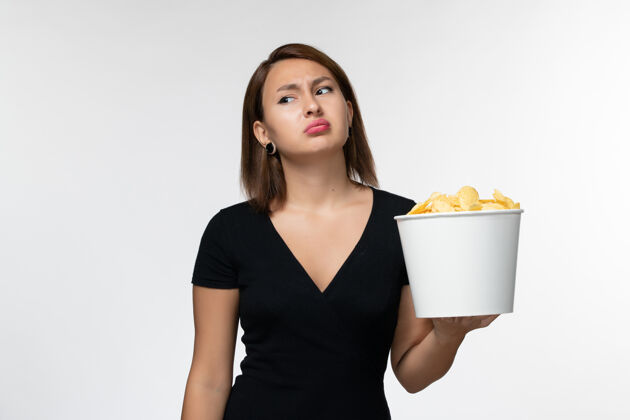 土豆正面图身穿黑色衬衫的年轻女性在白色表面上拿着薯片电影举行前面