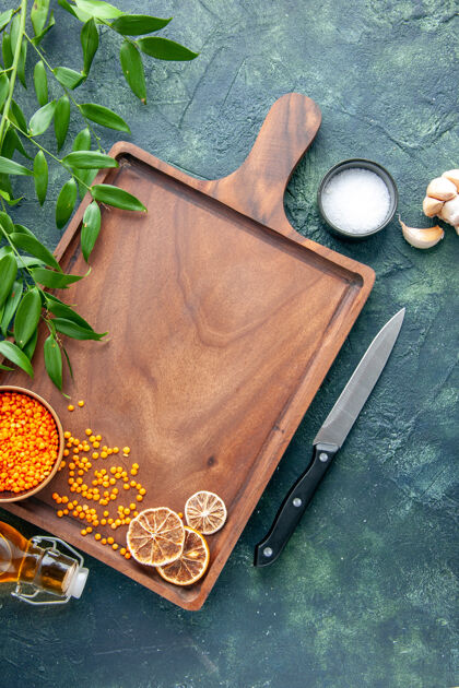 箱子俯视图棕色木制书桌 深蓝色表面上放着橙色小扁豆 古老的菜肴颜色 肉 屠夫 菜刀 食物肉扁豆容器