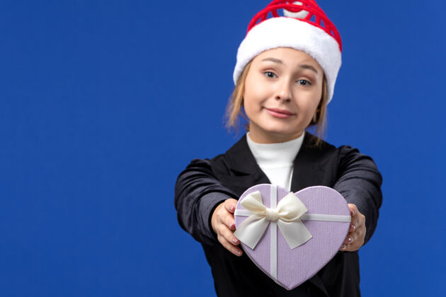 商人正面图年轻女士手持心形礼物在蓝色墙壁新年礼物节日看法形状心脏