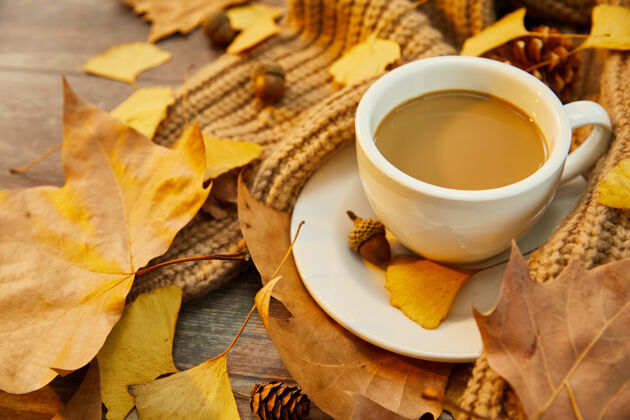 树叶一杯咖啡和秋叶在木头表面的特写镜头秋天热的树叶
