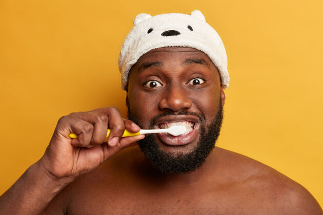裸体牙齿卫生 口腔科 牙齿美白概念皮肤黝黑的男人早上醒来 用牙刷刷牙新鲜看室内