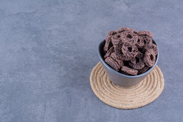 巧克力健康早餐 巧克力玉米圈放在石头上的黑碗里小吃菜能量