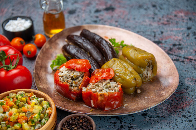 胡椒粉前视图茄子与煮熟的西红柿和甜椒与肉末填充在蓝色背景板内多尔玛晚餐地食物