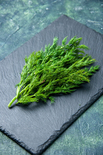 食物新鲜莳萝束在绿黑混合色背景的黑色砧板上的垂直视图垂直草药自然