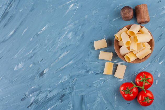 顶视图蓝色桌子上放着一个木制的碗 里面有新鲜的红番茄和香料午餐饮食复制空间