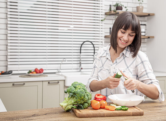 健康美丽的黑发女人微笑着在厨房内部模糊的背景上准备沙拉维生素厨房沙拉