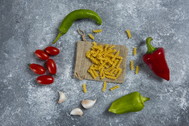 胡椒生螺旋通心粉配蔬菜放在大理石上美味生的袋装