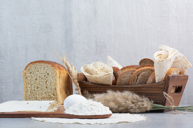 面粉在大理石背景上放一篮面包和洗手盆高质量照片烘焙切的面包
