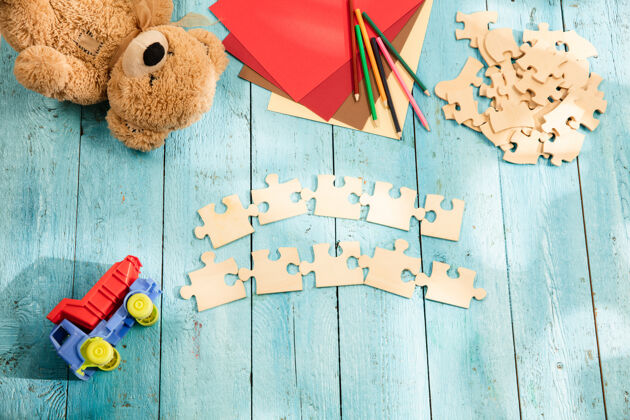 新的拼图 蜡笔 玩具卡车 泰迪熊和木头桌子上的纸童年和教育的概念学校碎片计划