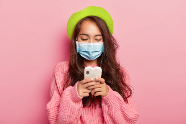 疾病有病的年轻黑发女子 专注于手机设备 戴着医用口罩 有健康问题支架预防防护