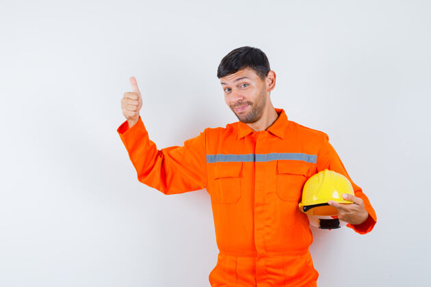 工厂戴着头盔的工业工人 穿着制服竖起大拇指 看上去很快乐正视图工程师生产工人