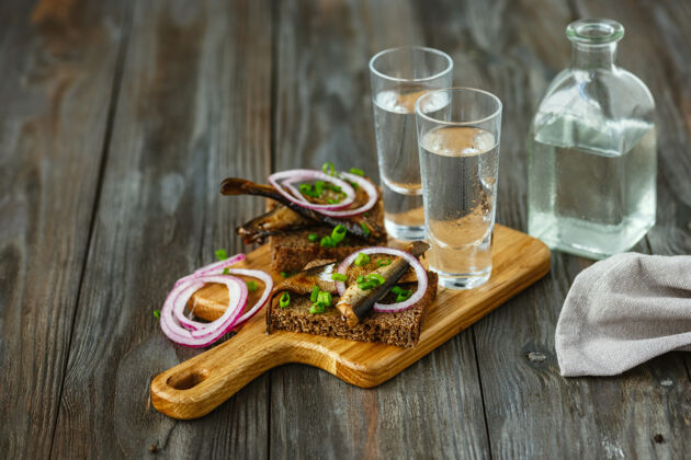 杜松子酒伏特加配鱼和面包烤面包放在木桌上举行补品蔬菜