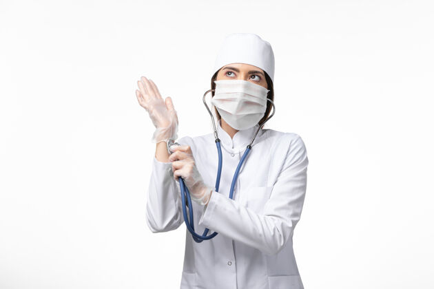 专业前视图：女医生穿着白色医疗服 戴着口罩 因大流行使用听诊器 白墙疾病 健康医学 大流行病毒-面具正面医生