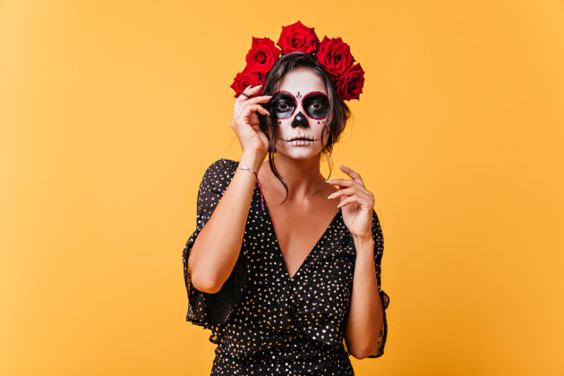 死亡之日戴着花冠和骷髅面具的黑皮肤女孩在万圣节的记忆中摆姿势拍照穿着不寻常服装的非凡模特的肖像幽灵服装墨西哥