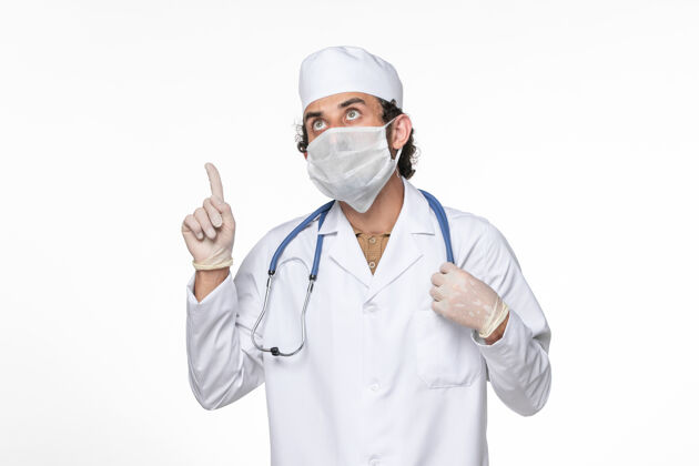 病毒正面图：男医生穿着医疗服 戴着口罩以防感染冠状病毒——并思考白墙病毒喷溅冠状病毒大流行防护医疗正面